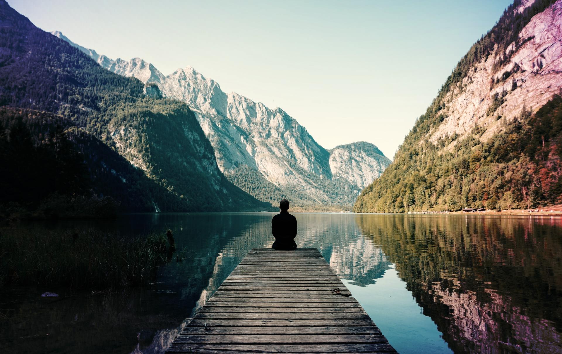 man sitting on gray dock